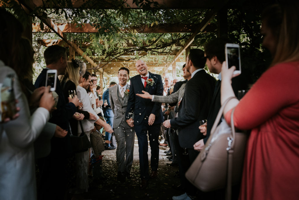 Married couple walking through confetti throwing guests