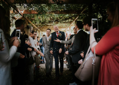 Married couple walking through confetti throwing guests